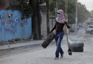 A supporter of presidential candidate Moise Jean-Charles carries a tyre in a barricade during protests after the announcement of the results of the presidential election, on a street in Port-au-Prince, Haiti, November 5, 2015. Ruling party candidate Jovenel Moise led voting in Haiti's Oct. 25 presidential election with 32 percent, followed by former government executive Jude Celestin with 25 percent, according to official results announced on Thursday. REUTERS/Andres Martinez Casares