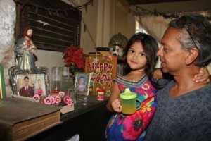 Lorne Ramsoomair holds his four-year-old daughter, Danielle, in front of a homemade shrine at his Couva home, which he built in memory of his wife and mother to their children, Crystal Boodoo-Ramsoomair, who died after a C-section at the San Fernando General Hospital in 2011